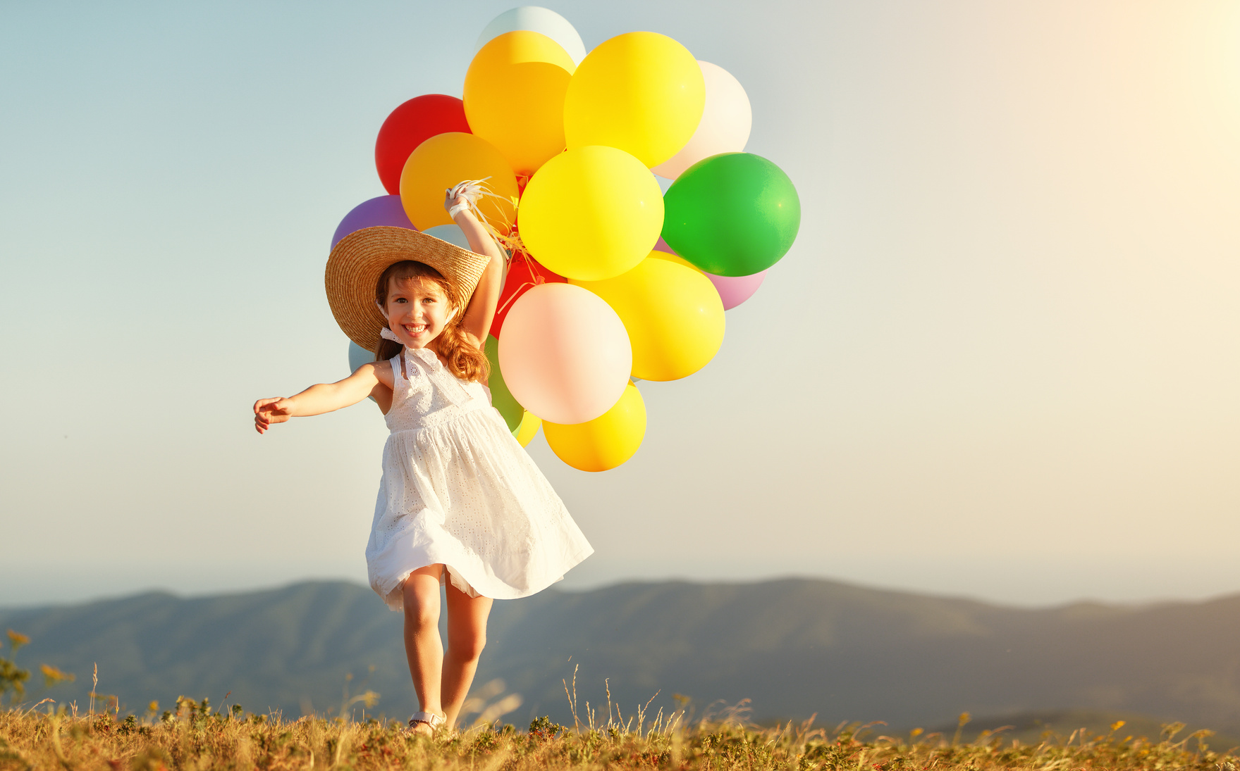 happy child with balloons at sunset in summer